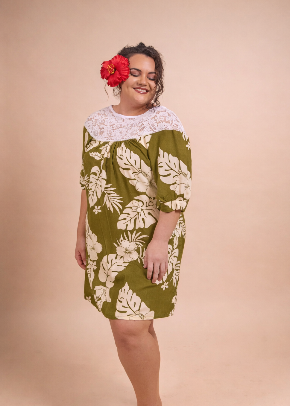 Women with a beautiful red hibiscus on her ear wearing a cute polynesian dress in green olive color with hibiscus pattern