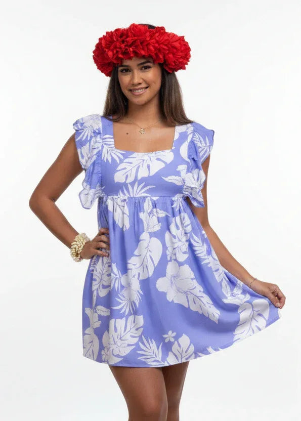 Woman wearing Bamboo Kultur’s “Hokulani” lavender floral Polynesian dress, one in the long version and the other in the short version, standing in a tropical setting