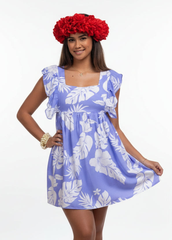 Woman wearing Bamboo Kultur’s “Hokulani” lavender floral Polynesian dress, one in the long version and the other in the short version, standing in a tropical setting