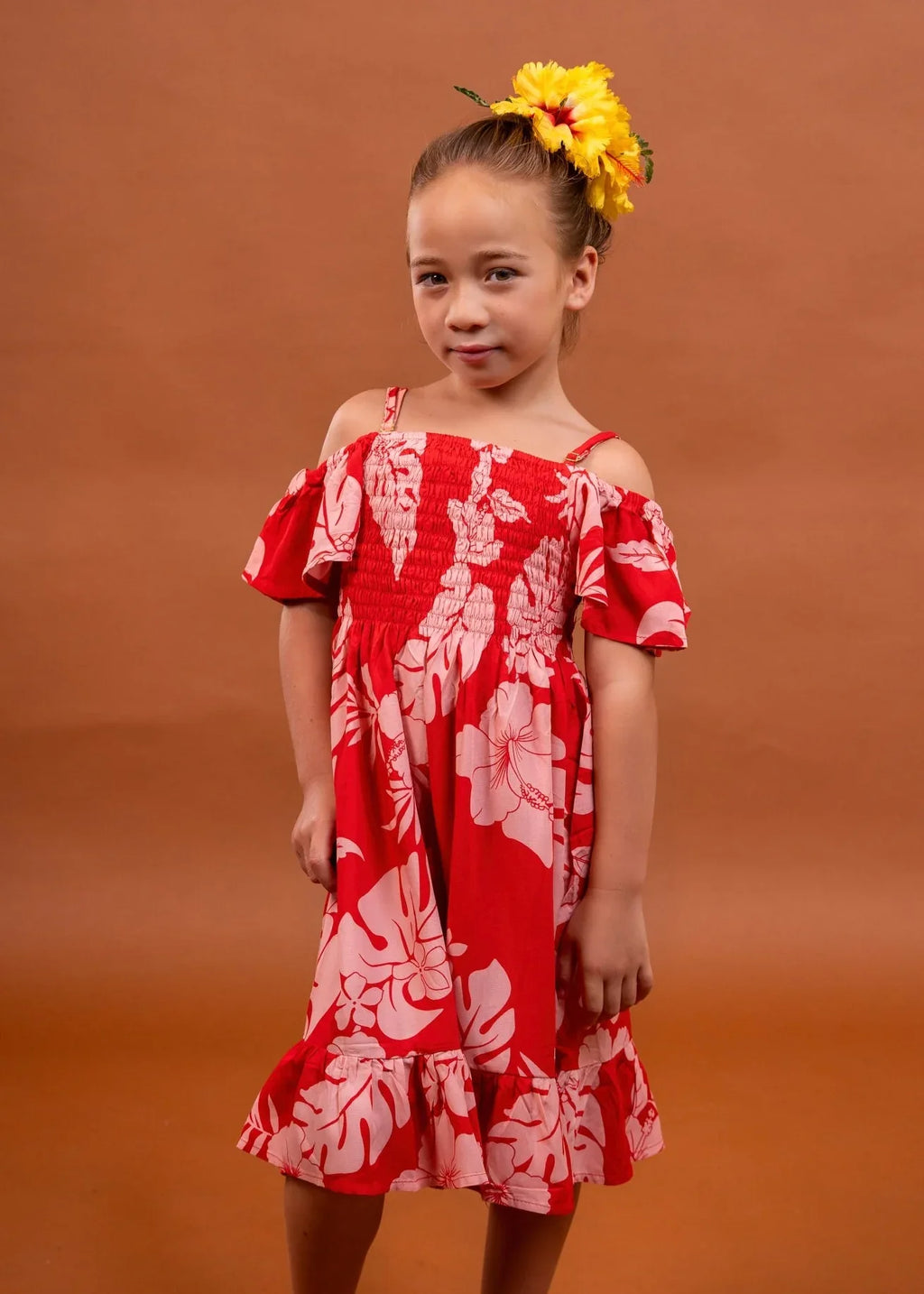 Cute little girl wearing a pareo dress in cherry tomato color in hibiscus pattern