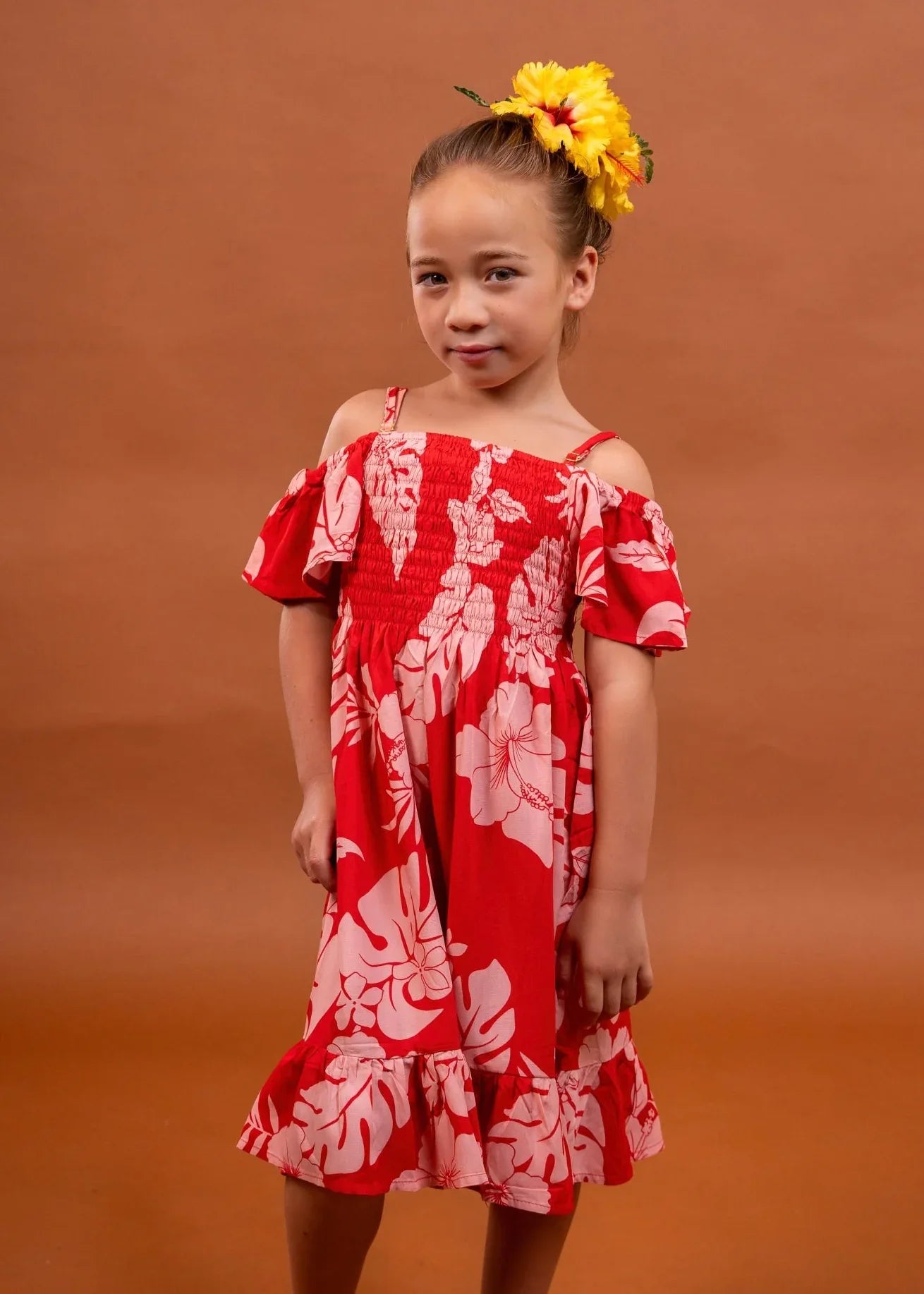 Cute little girl wearing a pareo dress in cherry tomato color in hibiscus pattern