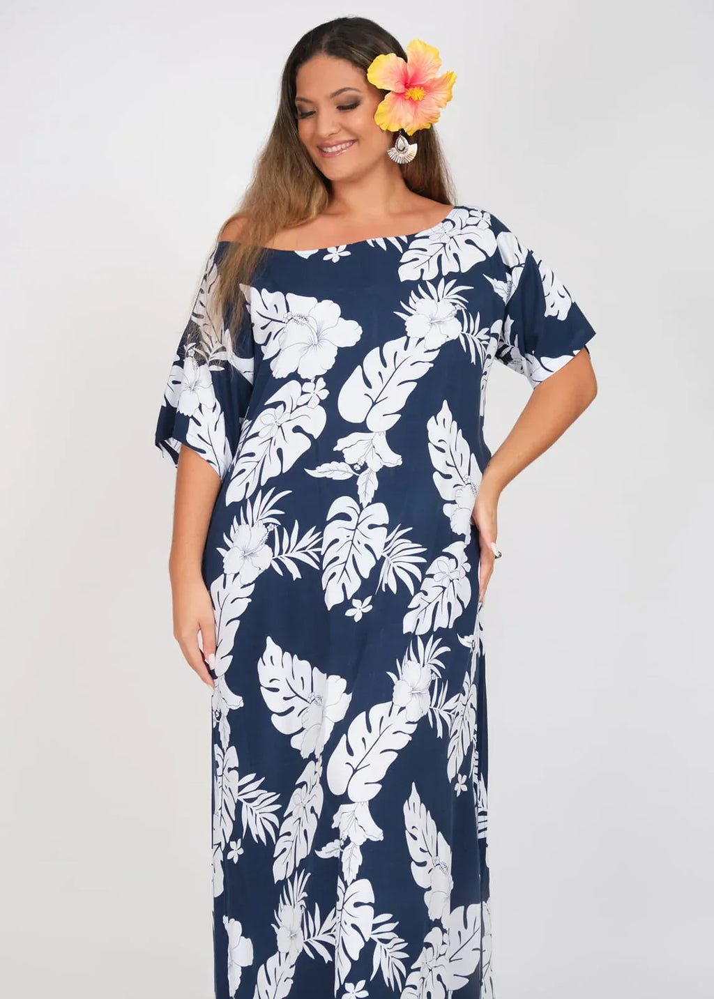 Women with a beautiful yellow hibiscus on her ear wearing a long polynesian dress in blue Navy color with hibiscus pattern
