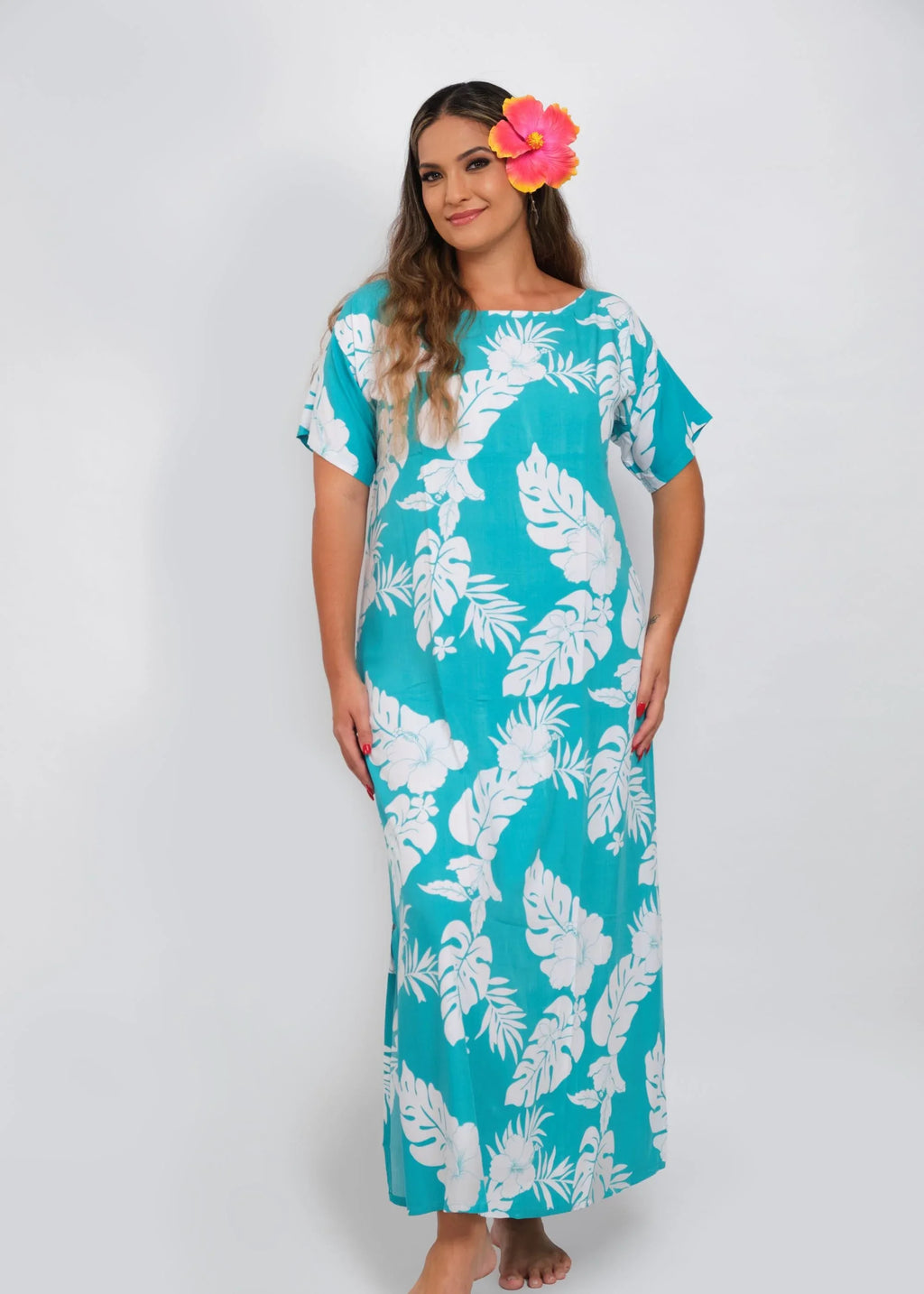 Women with a beautiful red hibiscus on her ear wearing a long polynesian dress in bright blue color with hibiscus pattern