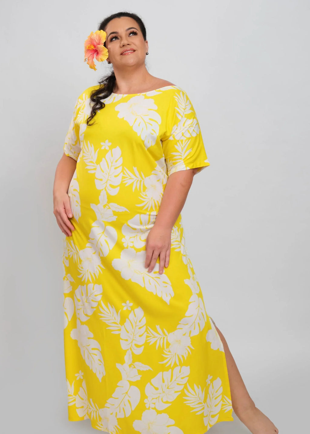 Women with a beautiful Yellow hibiscus on her ear wearing a long polynesian dress in Yellow color with hibiscus pattern