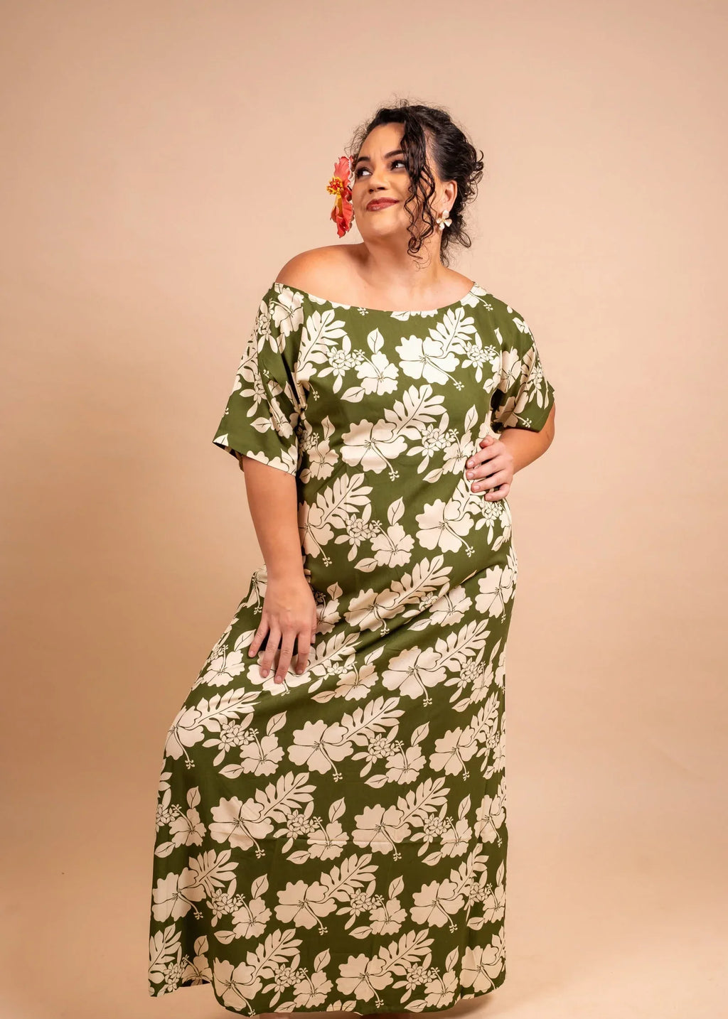 Women with a beautiful red hibiscus on her ear wearing a long polynesian dress in green olive color with hibiscus pattern
